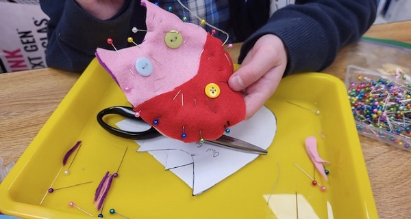 A child sewing a beginner sewing project with felt and buttons