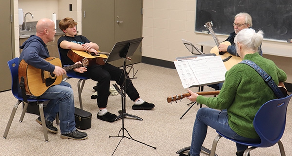 A small group of adults learning to play the guitar